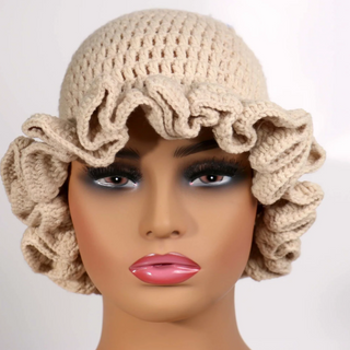 Beige crochet hat with ruffled edges on a mannequin head against a white background