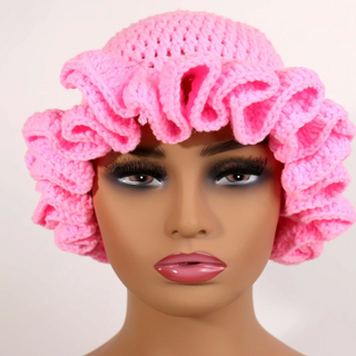 Mannequin head wearing a light pink crochet bonnet on a light background