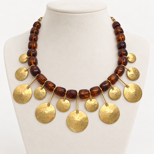 Amber brown resin bead necklace with hammered gold-tone metal discs on an ivory bust