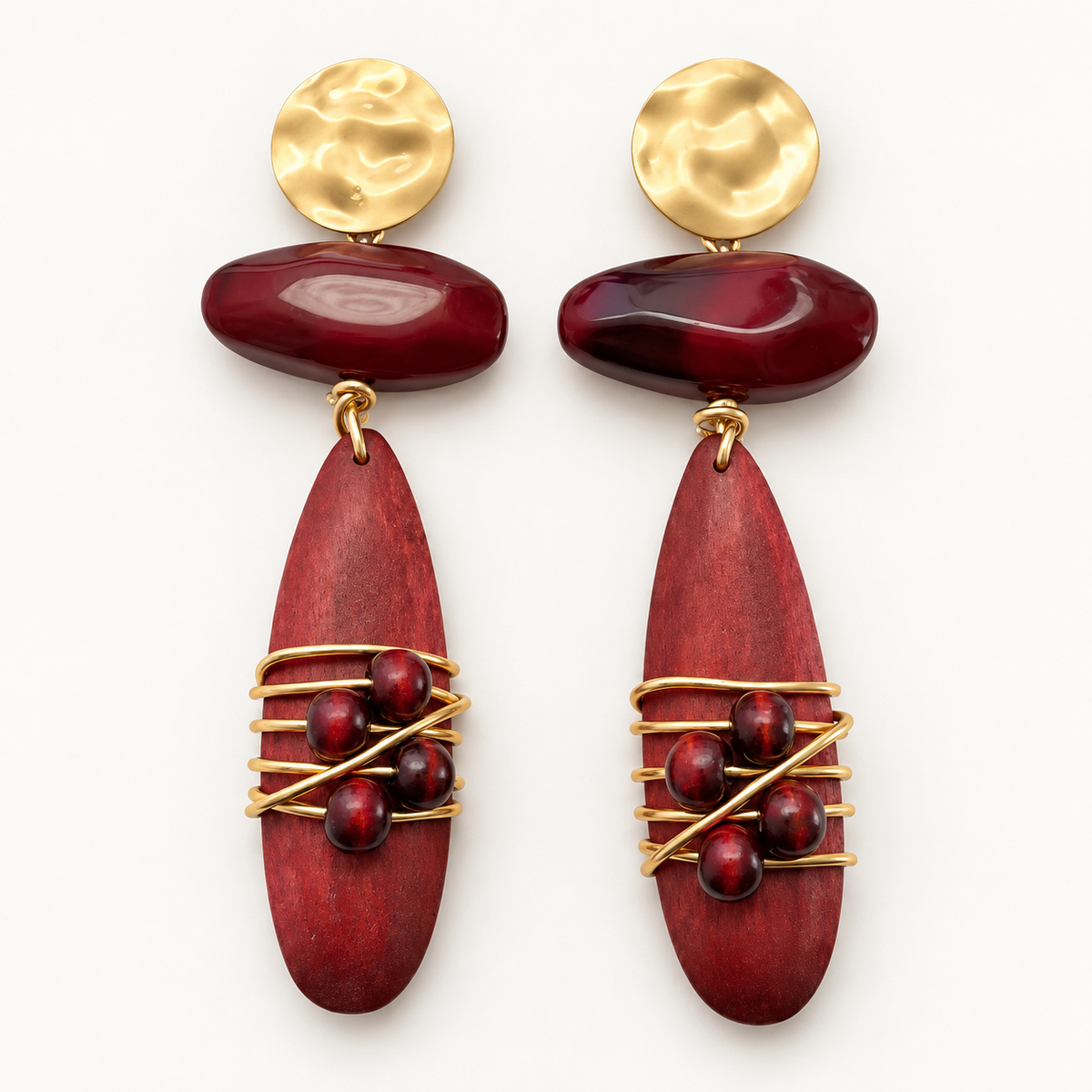 Burgundy wood and gold-tone metal drop earrings lying flat on a light background