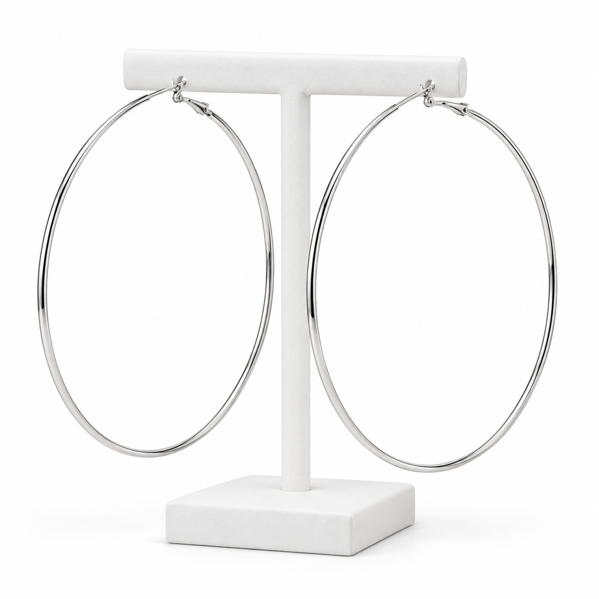 Large slim silver-tone hoop earrings hanging on a white holder