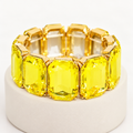 Yellow rectangular crystal stretch bracelet on an ivory display