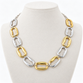 Gold-tone and silver-tone sculpted link necklace on a pale display bust
