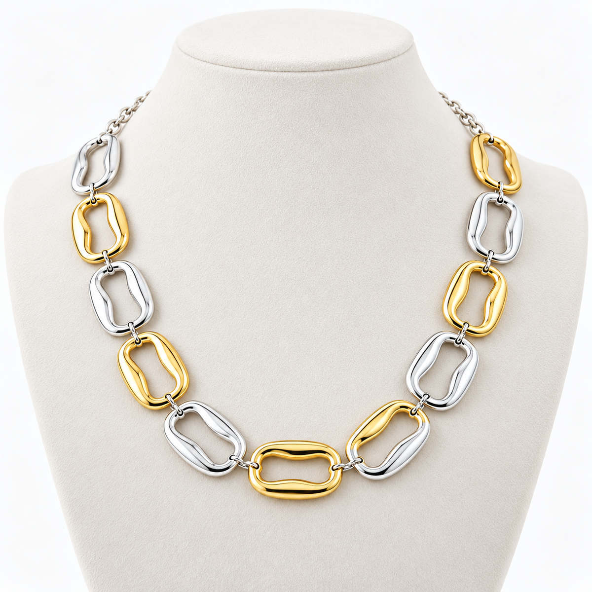 Gold-tone and silver-tone sculpted link necklace on a pale display bust