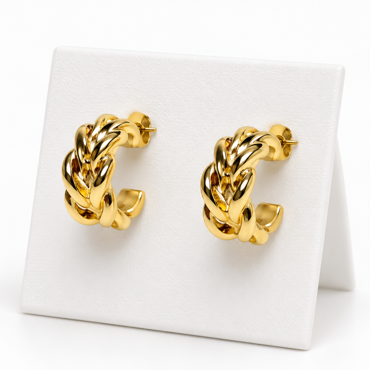 Small gold-tone braided open hoop earrings with post backs on a white holder