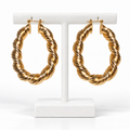 Gold-tone twisted oval hoop earrings on a white earring hanger