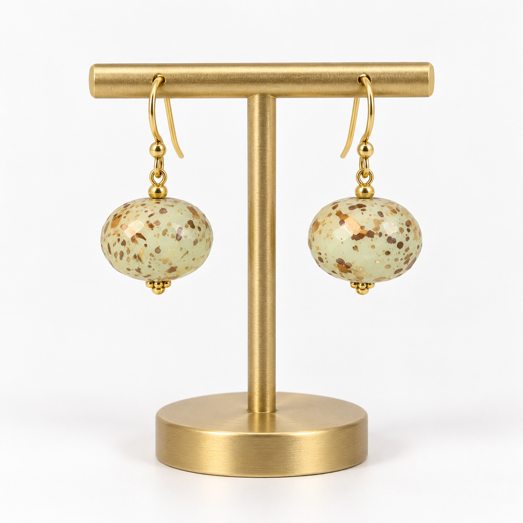 Matching ivory speckled fishhook earrings on a small holder