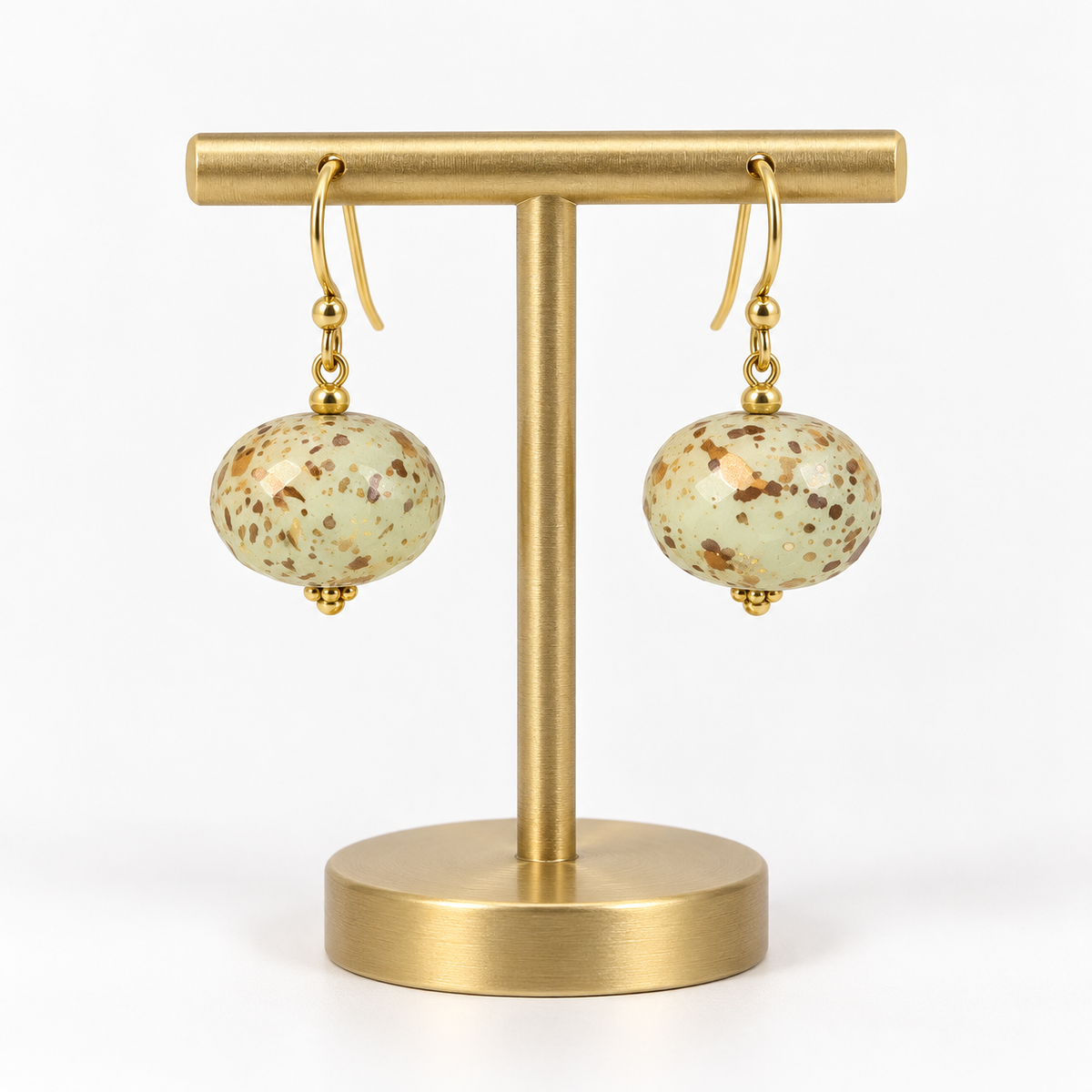 Matching ivory speckled fishhook earrings on a small holder