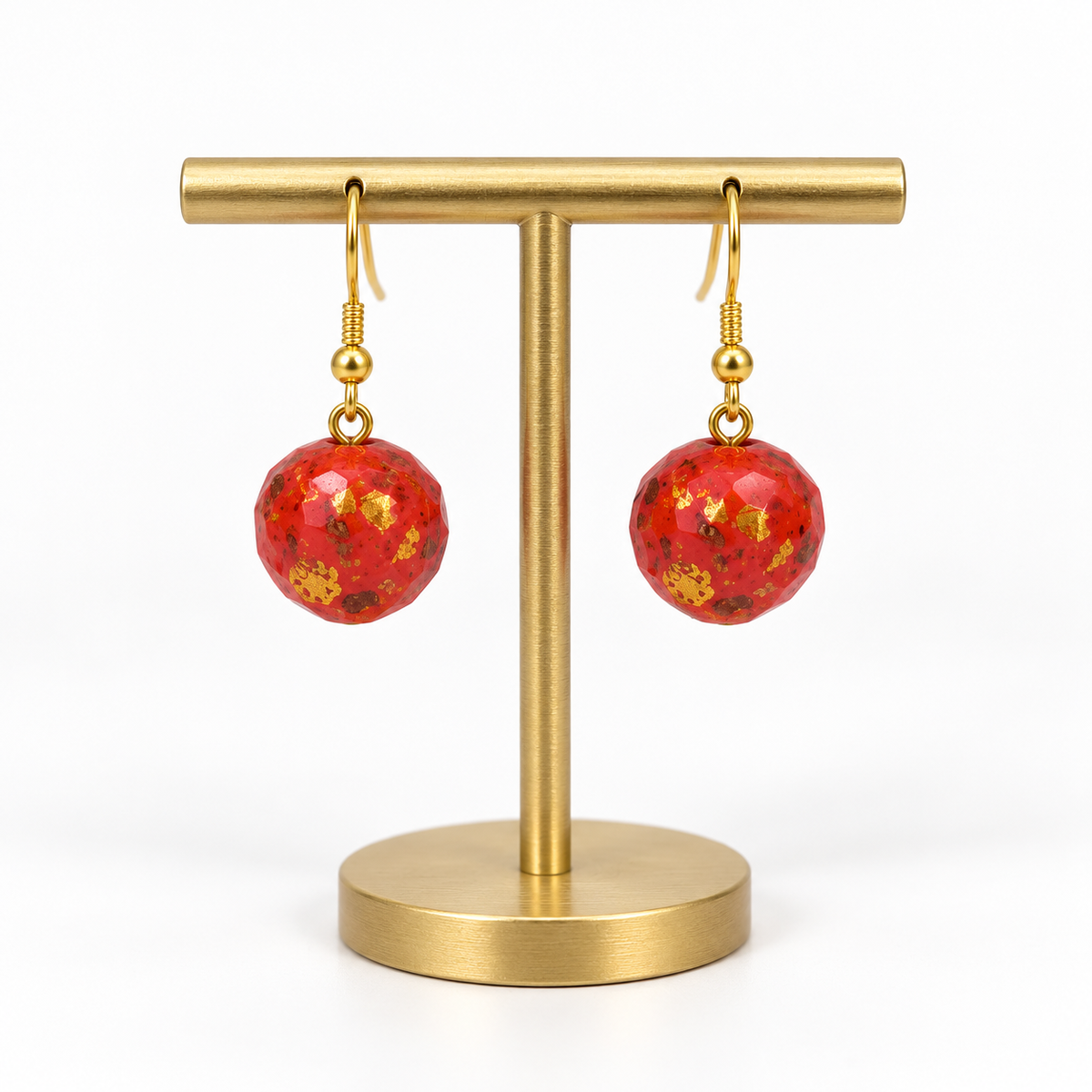 Matching red speckled fishhook earrings on a small holder