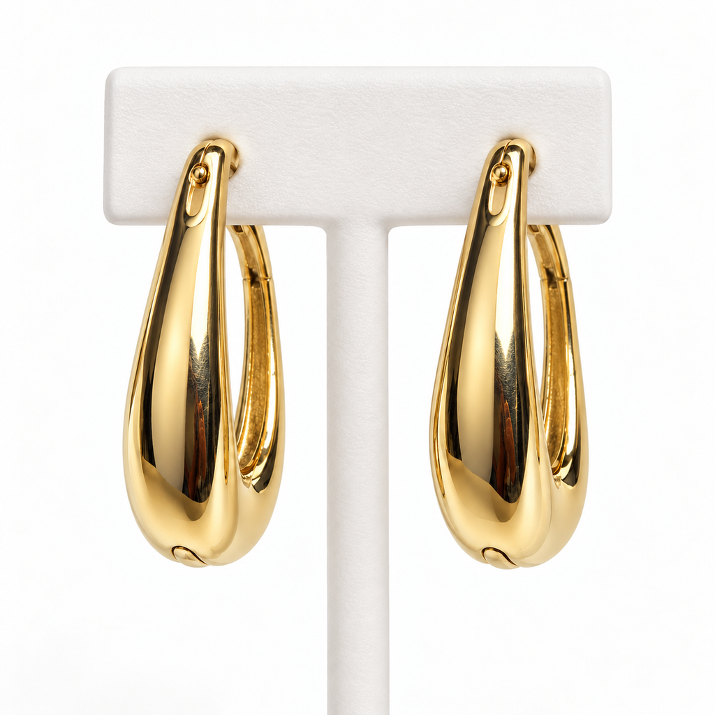 Gold-tone tapered hoop earrings hanging on a white holder