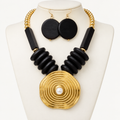 Black wood and gold-tone metal necklace with a fashion pearl centerpiece on an ivory bust
