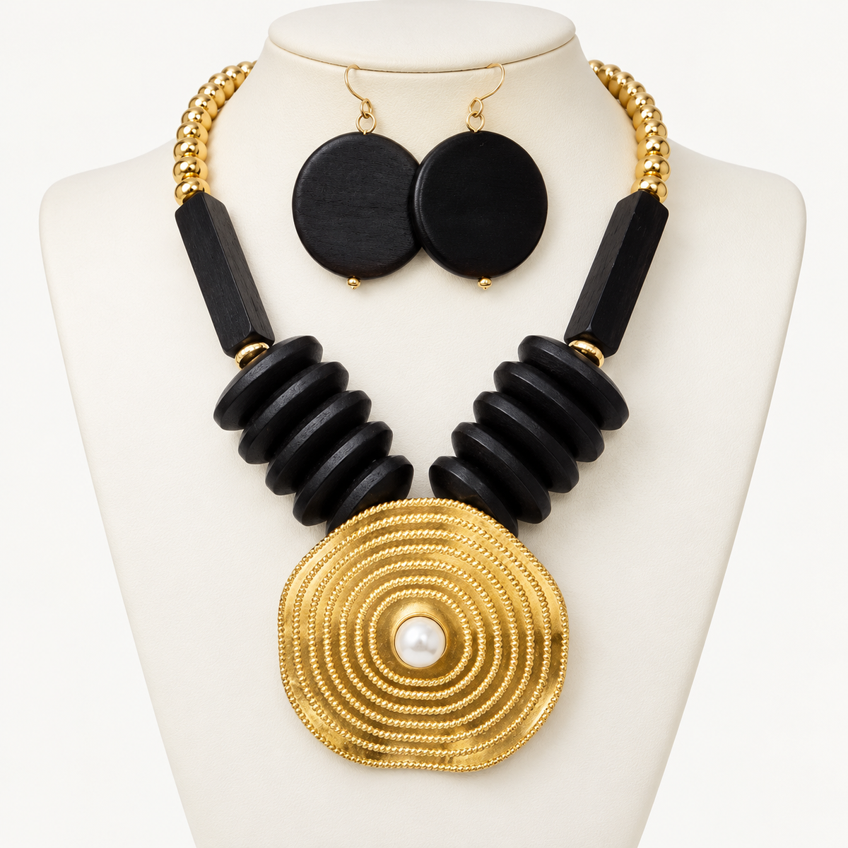 Black wood and gold-tone metal necklace with a fashion pearl centerpiece on an ivory bust