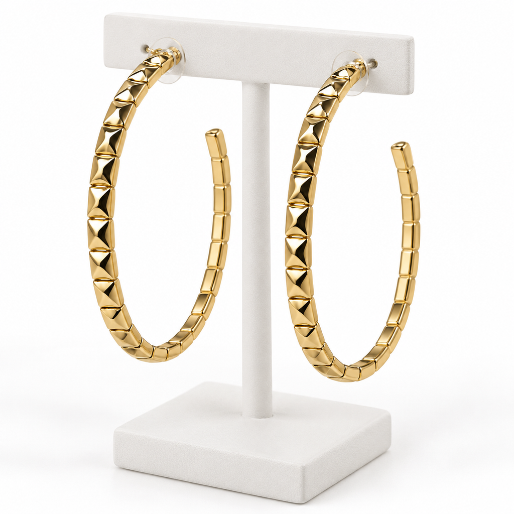 Large gold-tone faceted open hoop earrings with post backs on a white holder