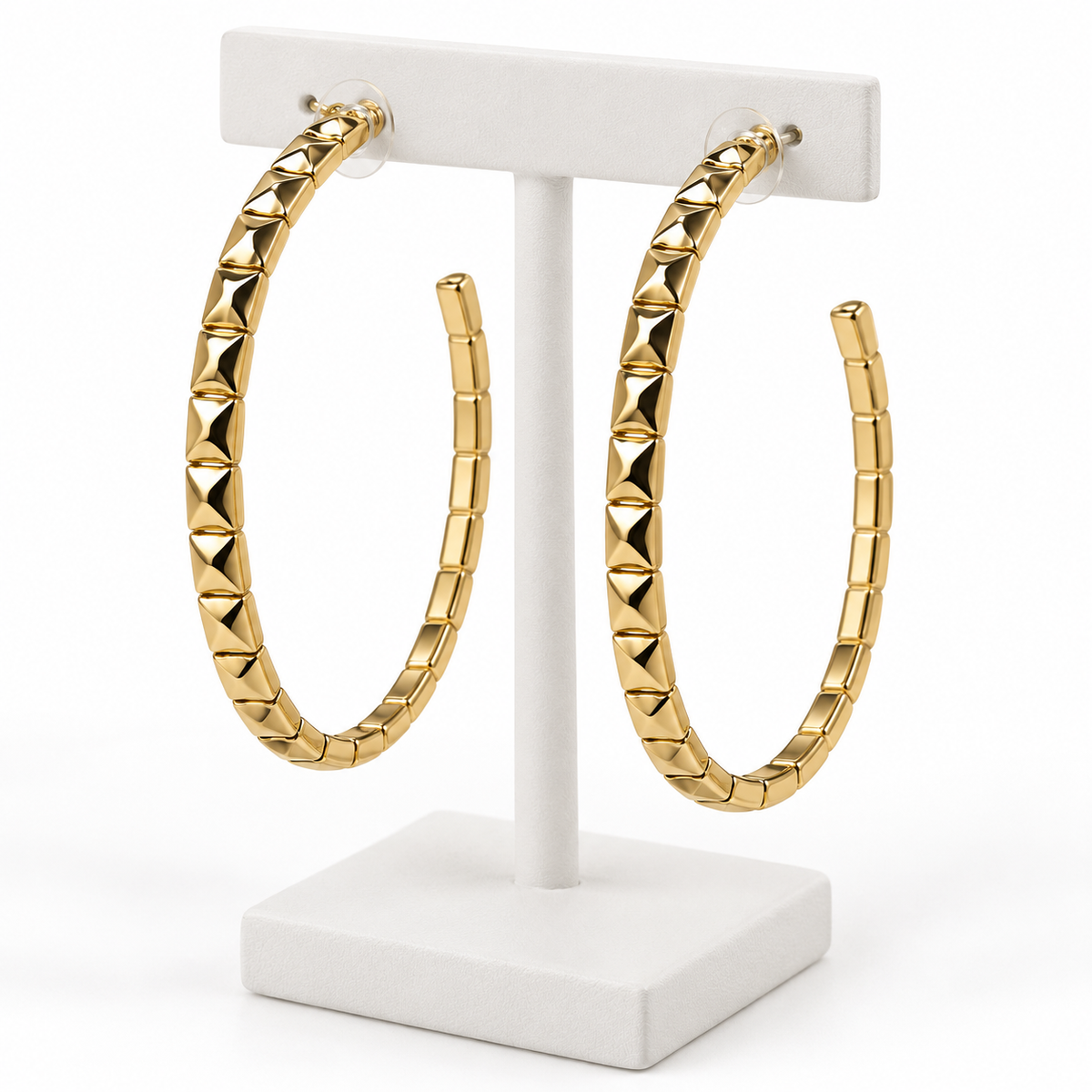 Large gold-tone faceted open hoop earrings with post backs on a white holder