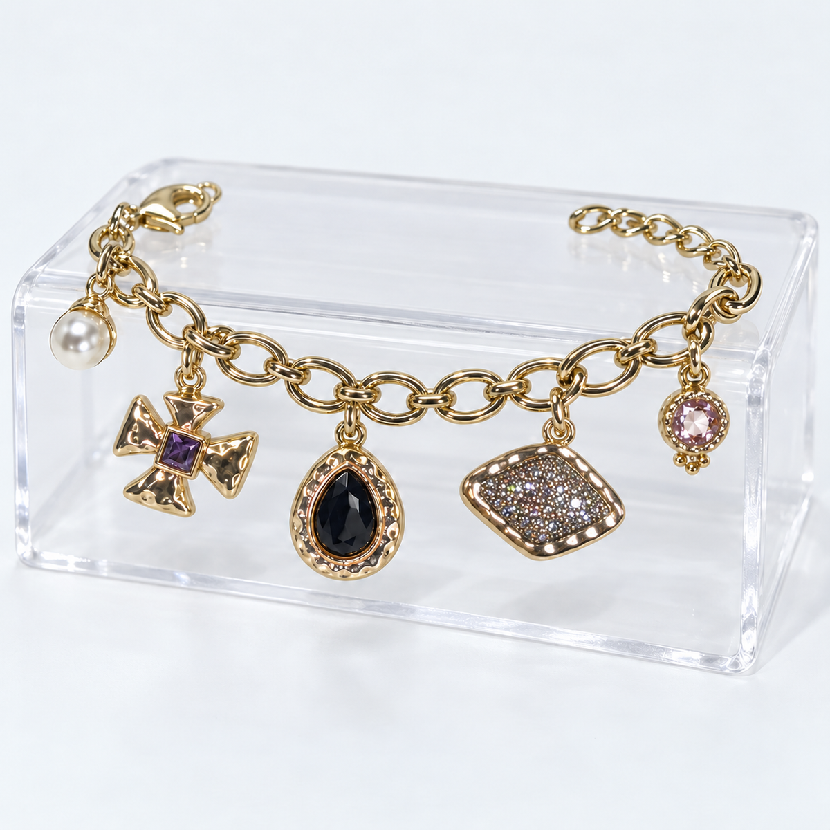 Golden Story charm bracelet on a clear acrylic display with all five charms hanging naturally