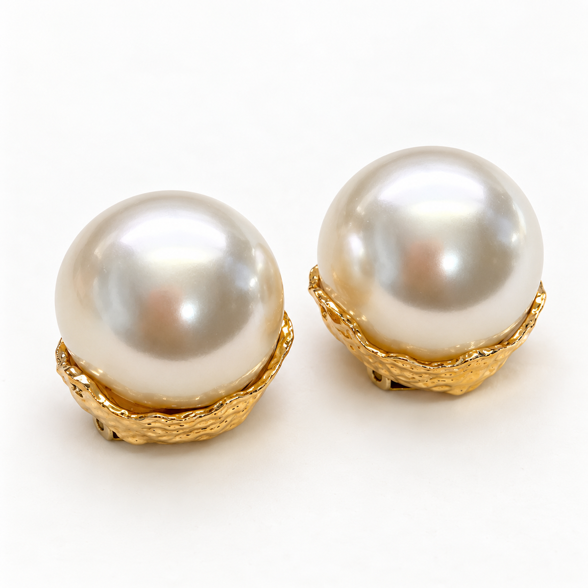 Oversized ivory pearl-look clip-on earrings lying on a light background