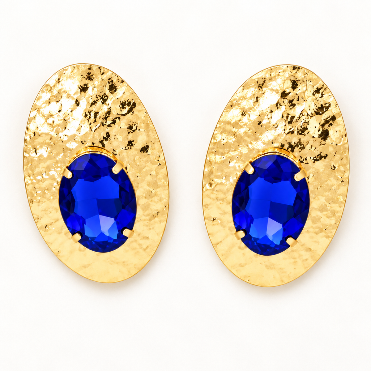 Blue faceted-stone hammered gold-tone oval post-back earrings laid flat on a near-white background