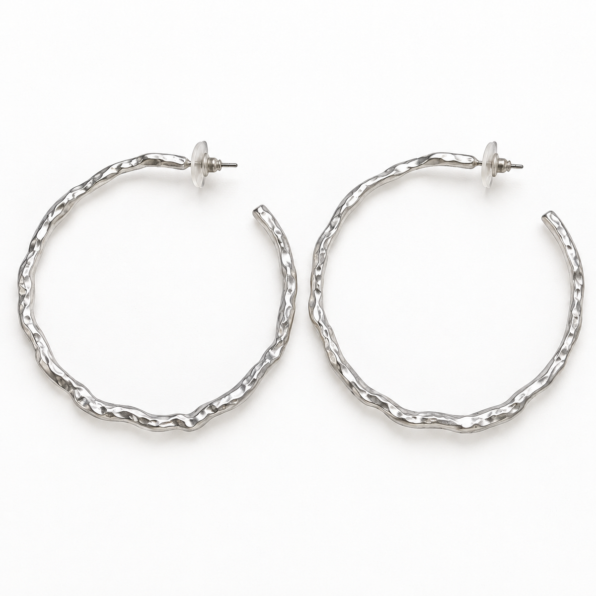 Pair of matte silver-tone wavy post-back hoop earrings laid flat on a white surface