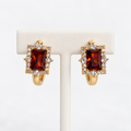 Amber rectangular halo gemstone huggie earrings on an earring holder