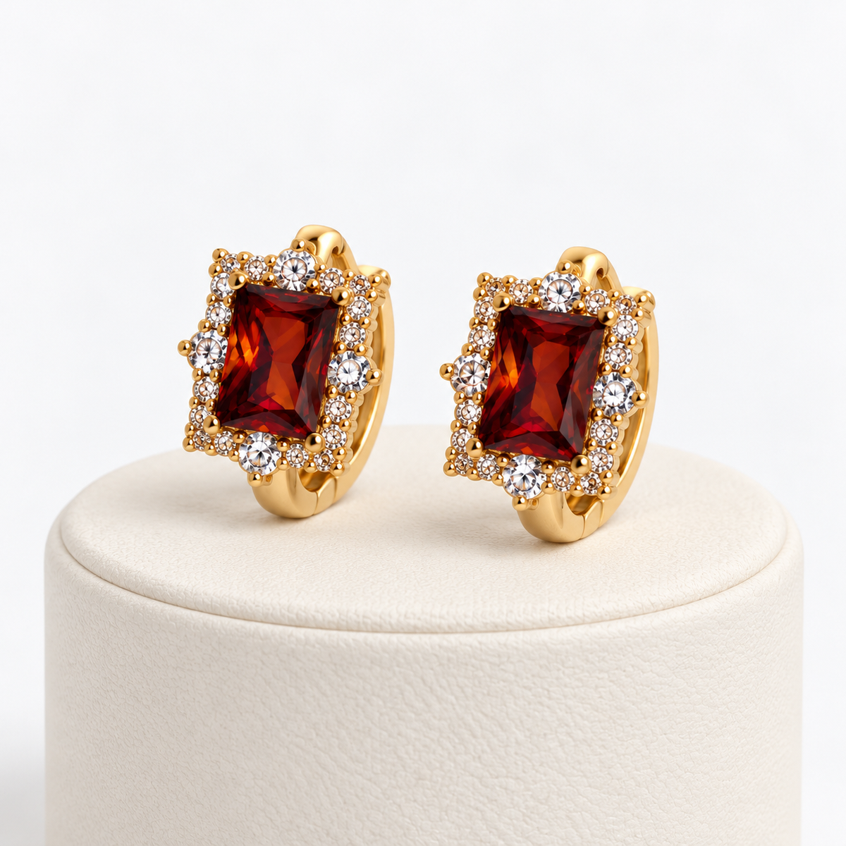 Amber rectangular halo gemstone huggie earrings on an ivory pedestal