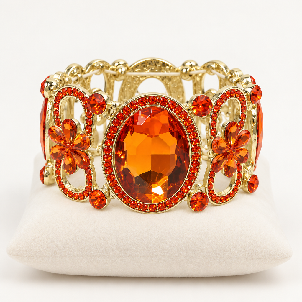 Orange crystal stretch bracelet with gold-tone floral openwork on an ivory cushion