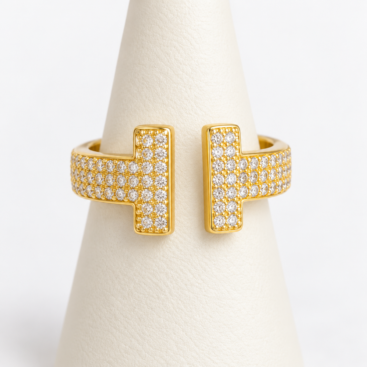 Gold adjustable double-bar ring with clear pavé stones on an ivory ring holder