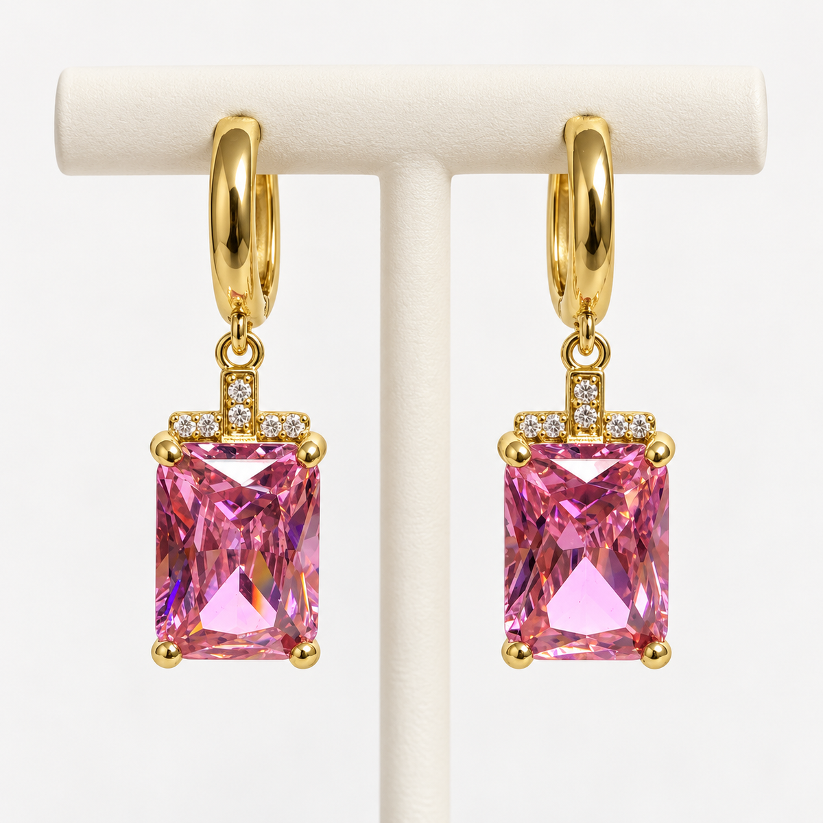 Gold and pink rectangular gemstone drop huggie earrings, on an earring holder