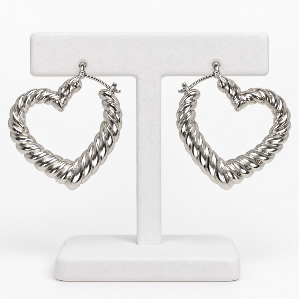 Silver-tone ribbed heart-shaped hoop earrings hanging on a white holder