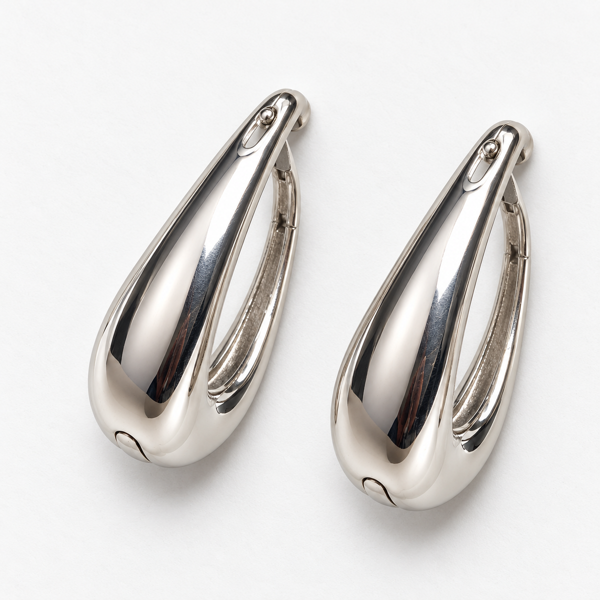 Silver-tone tapered hoop earrings lying flat in the same direction