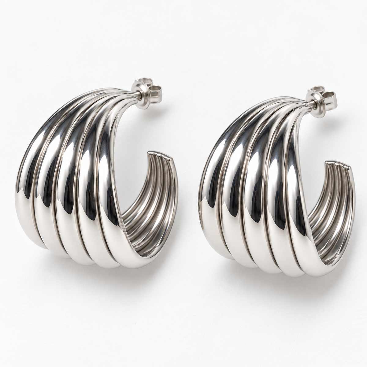Silver-tone ribbed open hoop earrings lying flat, showing the sculpted bands and post backs