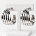Silver-tone ribbed open hoop earrings with post backs on a white holder