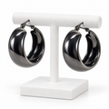 Dark gunmetal medium wide hoop earrings hanging on a white holder