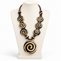 Black and cream spiral pendant necklace on a tall ivory display bust