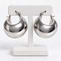 Pair of polished silver stainless steel chunky crescent hoop earrings on a white holder