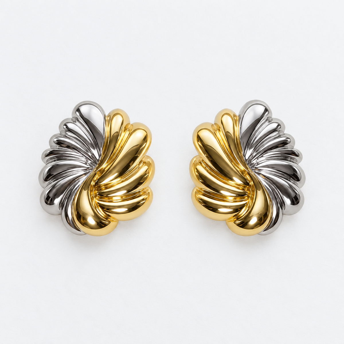 Pair of sculpted gold-tone and silver-tone leaf post-back stud earrings laid flat
