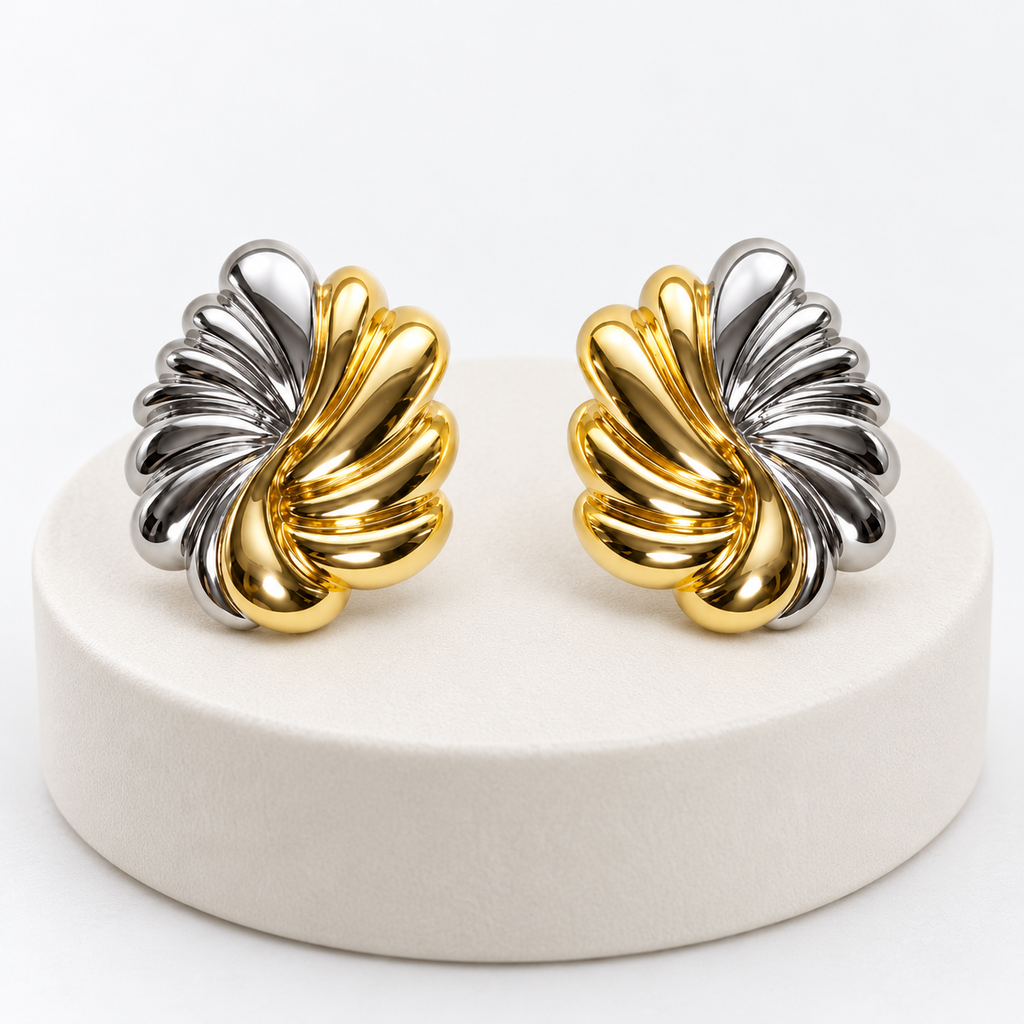 Pair of sculpted gold-tone and silver-tone leaf post-back stud earrings on an ivory pedestal