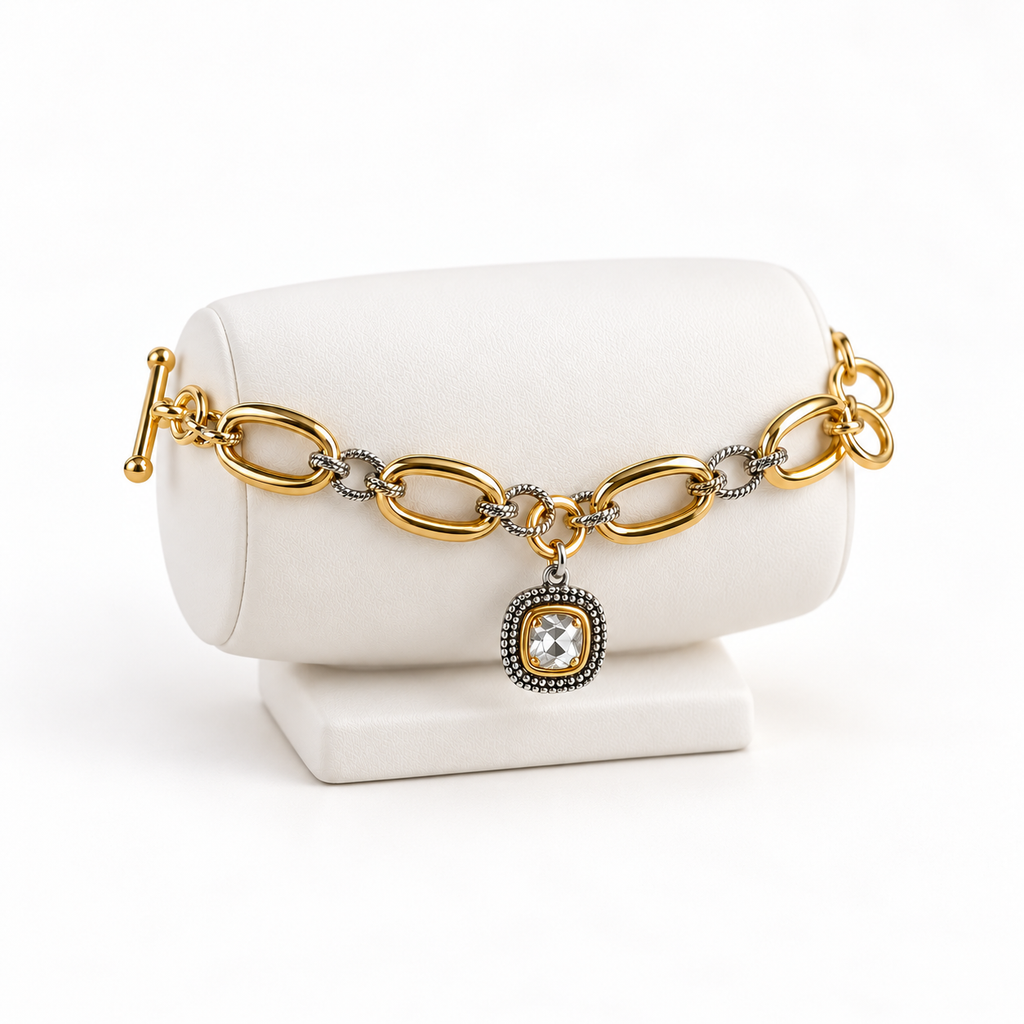 Two-tone oval link bracelet with clear square charm on a white bracelet holder