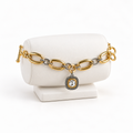 Two-tone oval link bracelet with clear square charm on a white bracelet holder